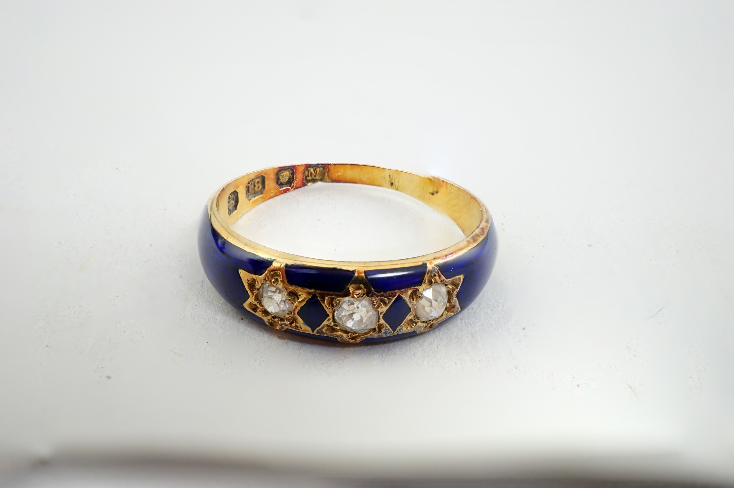 A late Victorian 18ct gold, three stone diamond and blue enamel set ring